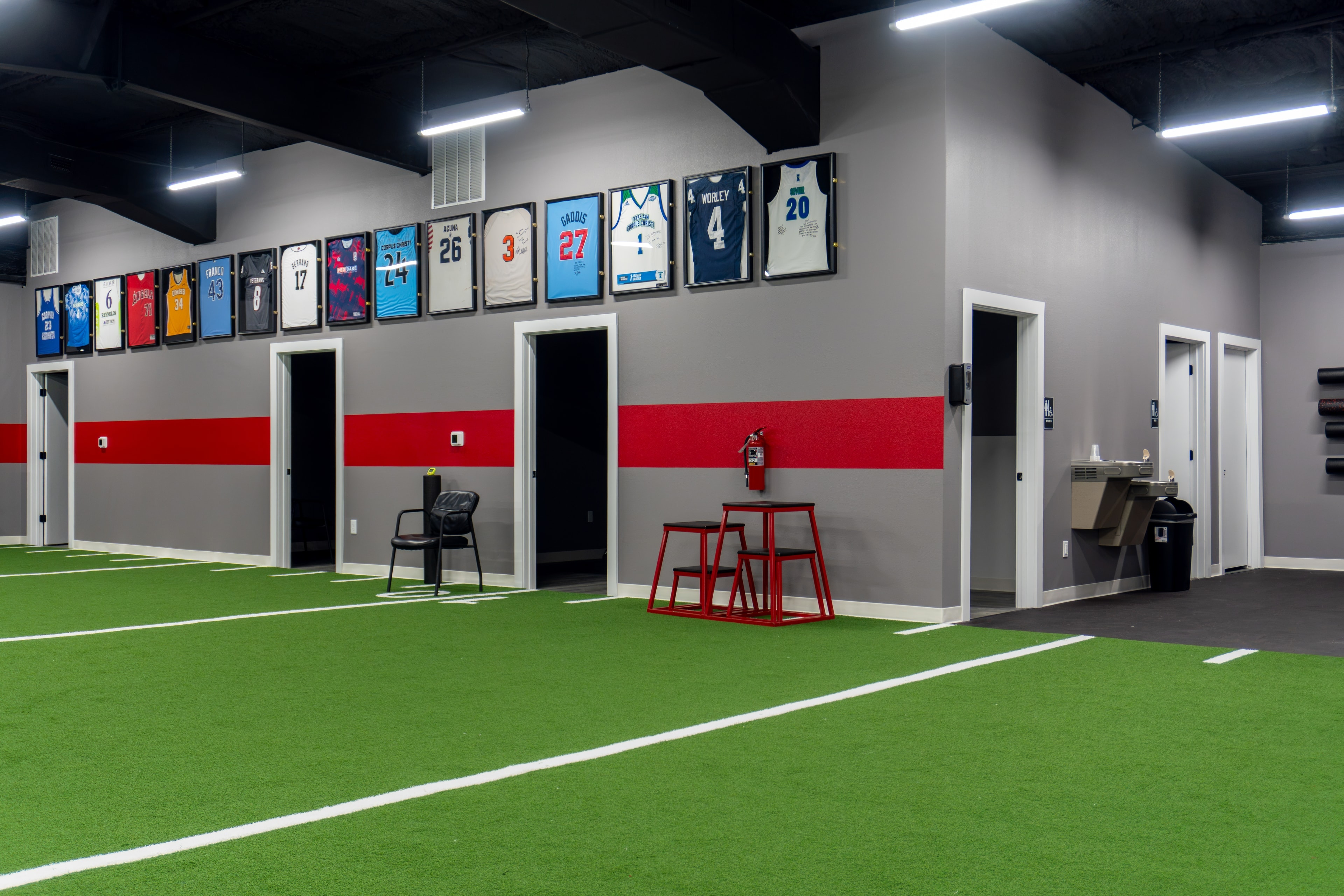 The Training Room Corpus Christi turf field with framed jerseys wall