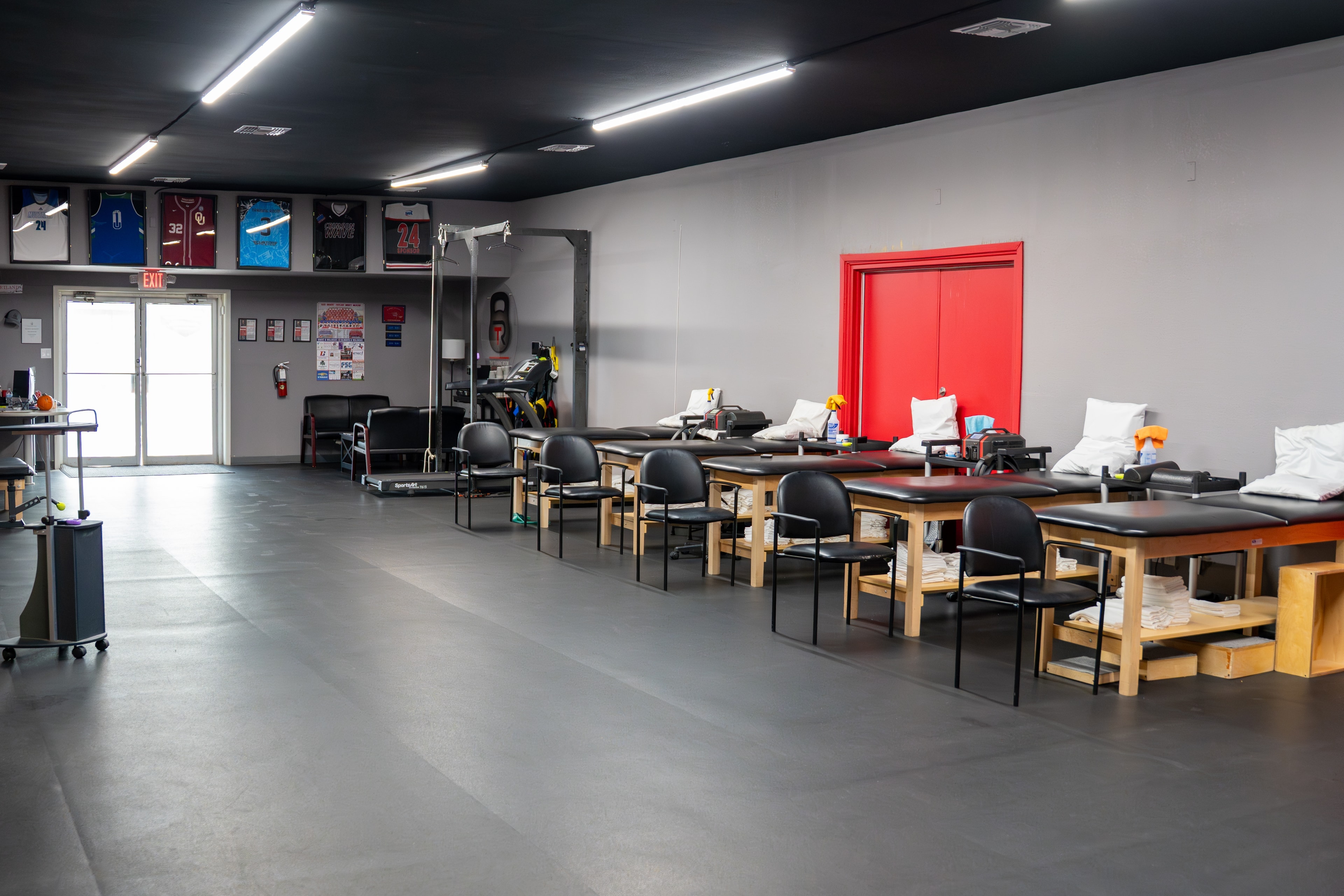 The Training Room Portland PT floor with framed jerseys and red double doors